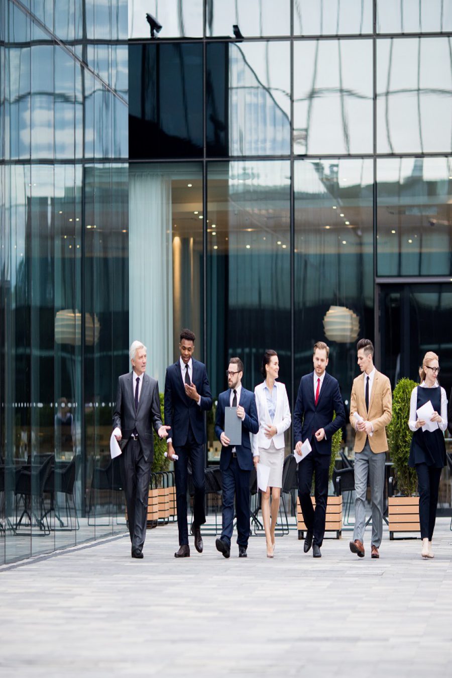 Large group of business people walking along modern business center and talking in urban environment